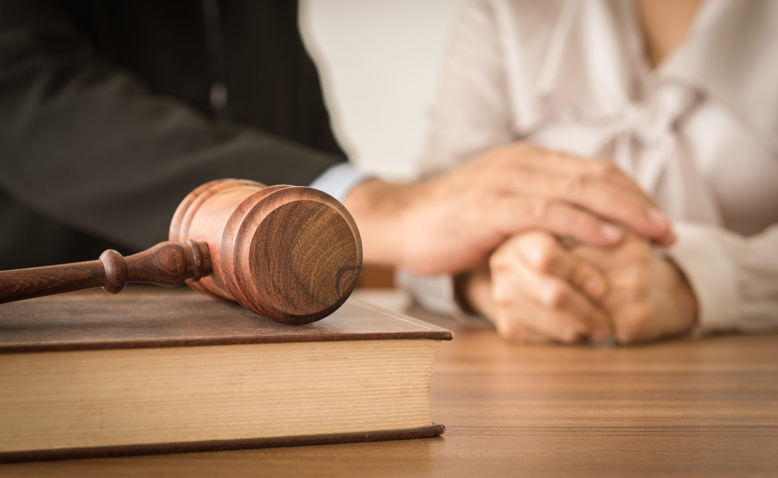 A lawyer with a client and a gavel on top of a book.